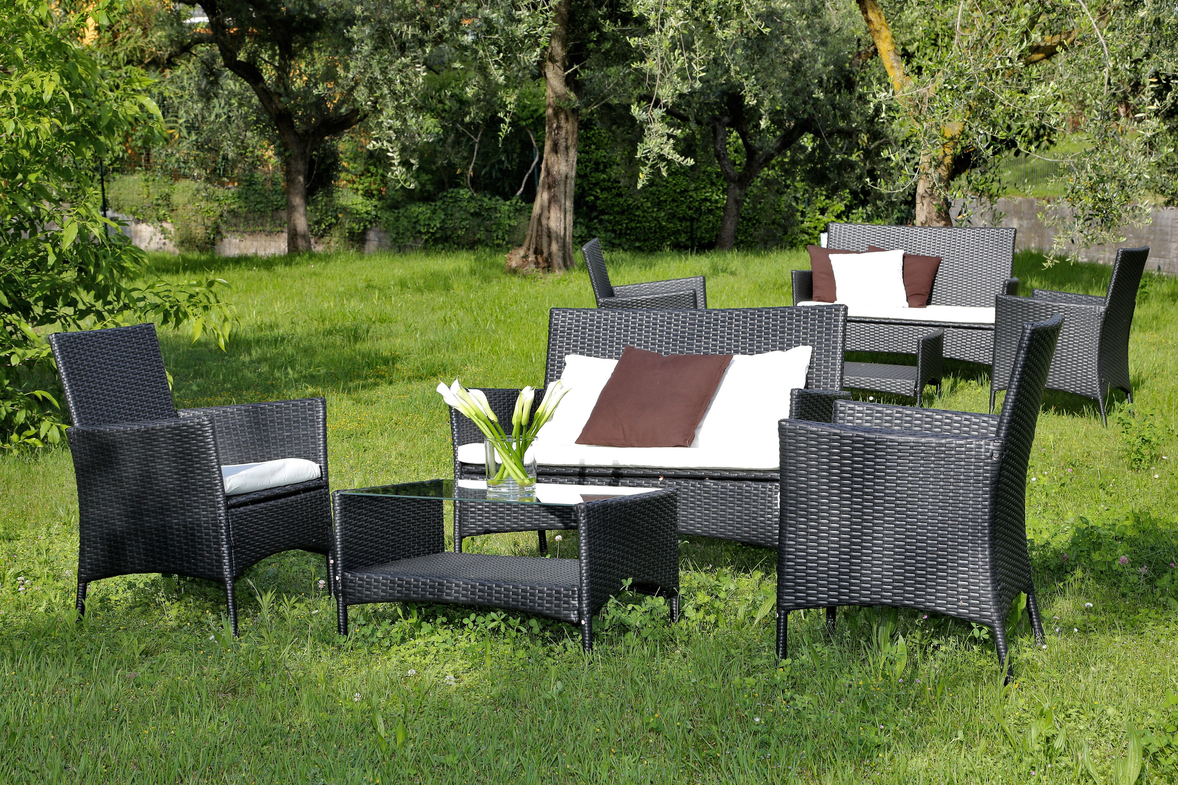 Outdoor wicker furniture with cushions and a vase of flowers.