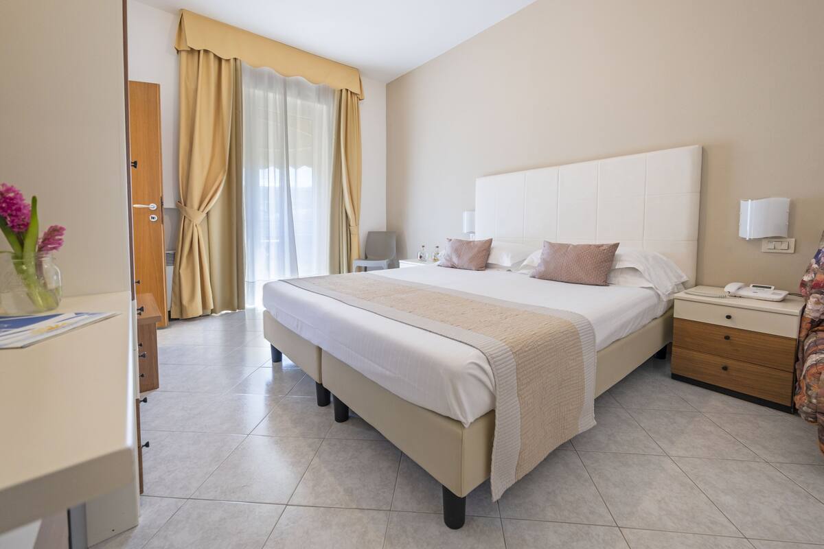 Une chambre d’hôtel avec un grand lit, des tables de chevet, un bureau et une chaise.