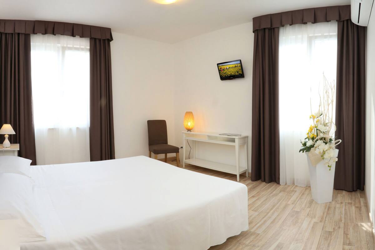 Une chambre d’hôtel équipée d’un lit, d’un bureau, d’une chaise, d’une télévision et d’une lampe.