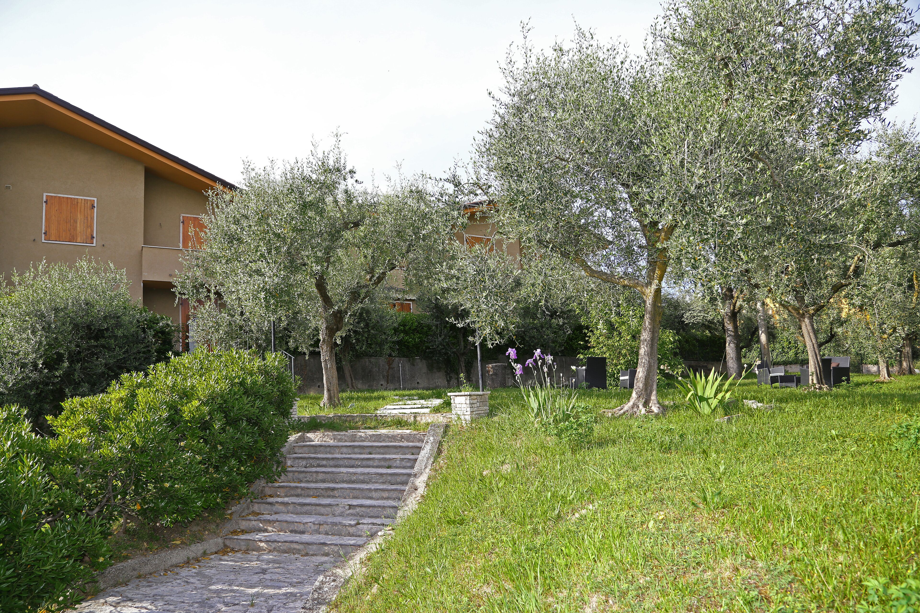 A residential area with a stone staircase leading to a building with a beige facade and wooden shutters.