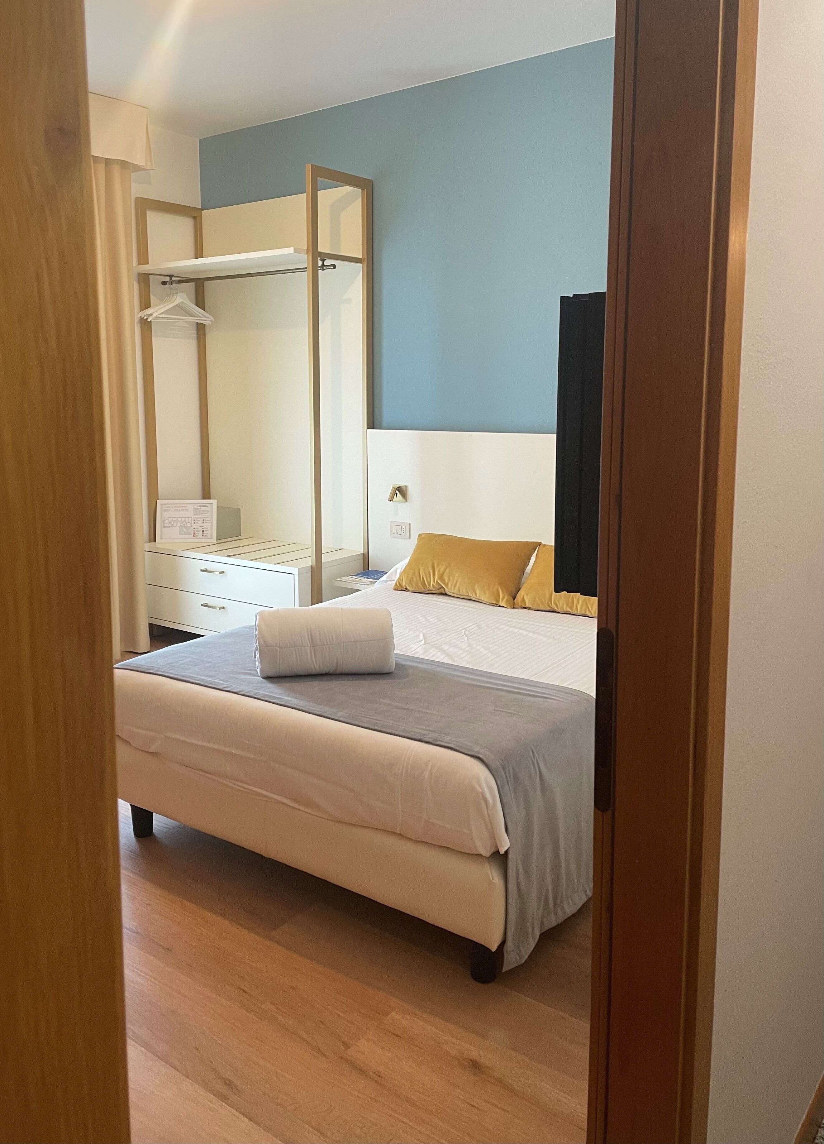 Un dormitorio con cama, mesita de noche, espejo y armario.