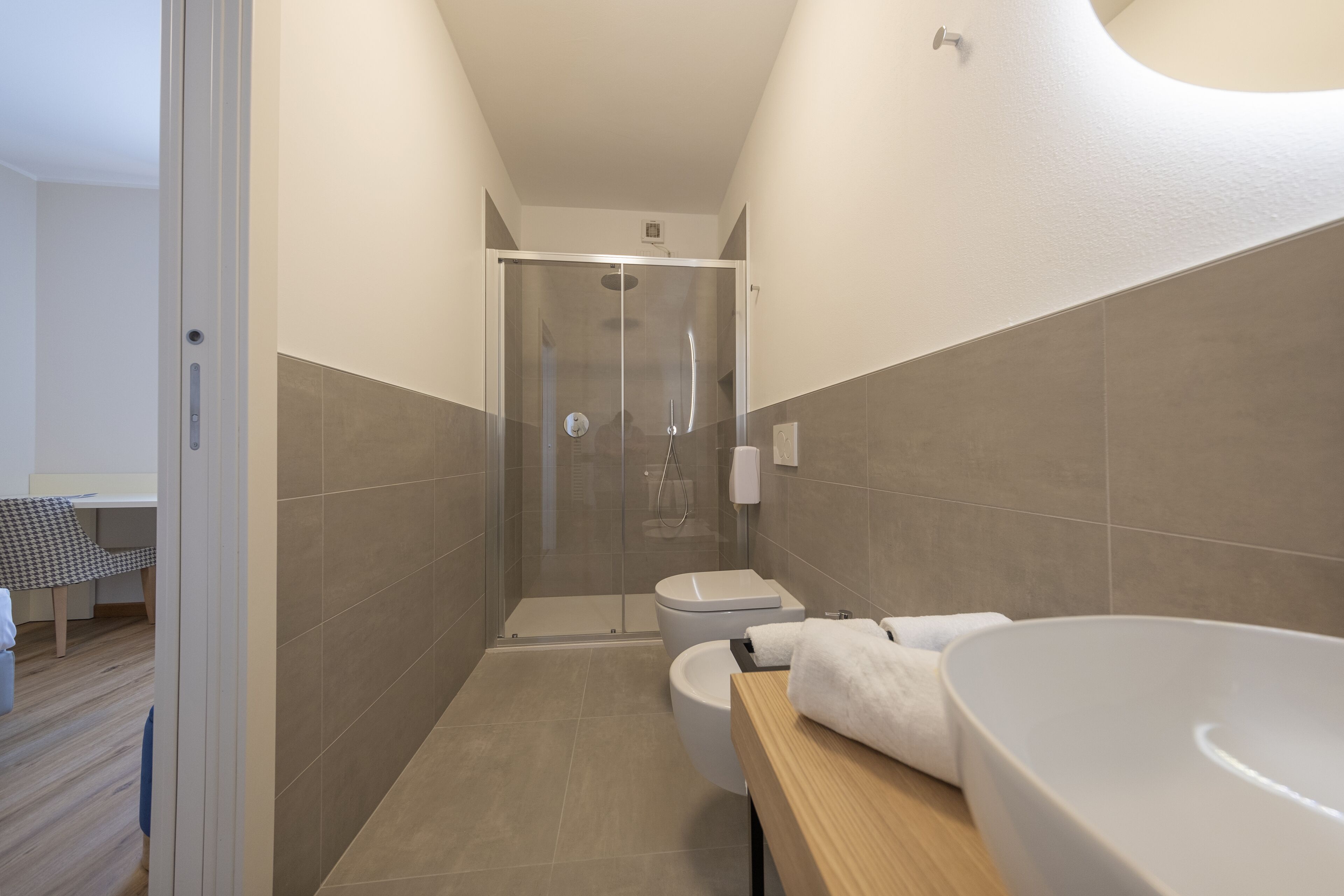 A modern bathroom with a glass-enclosed shower, a white toilet, and a large bathtub.