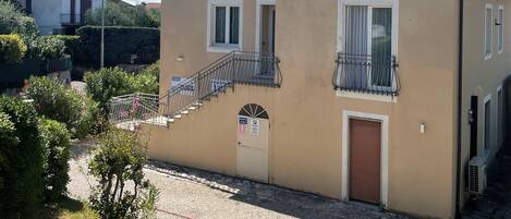 A two-story building with a beige facade, a small balcony, and a ground-level entrance.