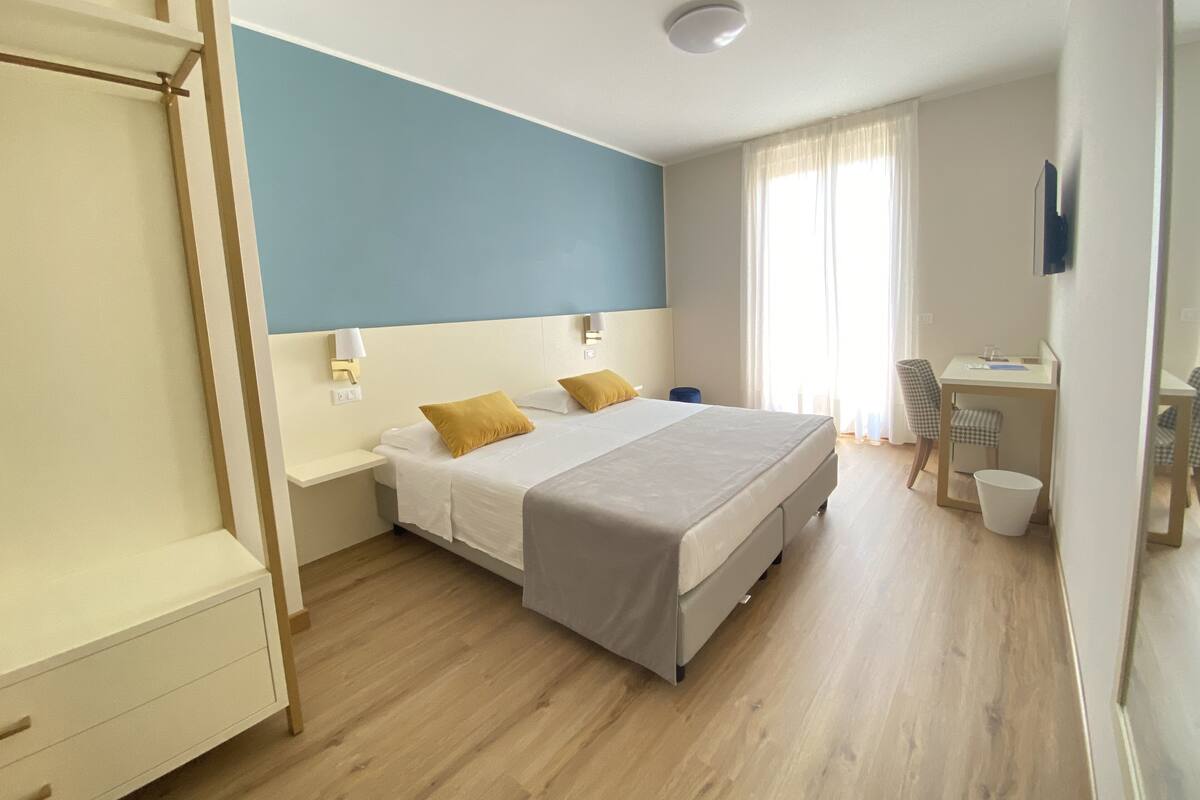 Une chambre d’hôtel moderne équipée d’un lit, de tables de chevet, d’un bureau et d’une chaise.