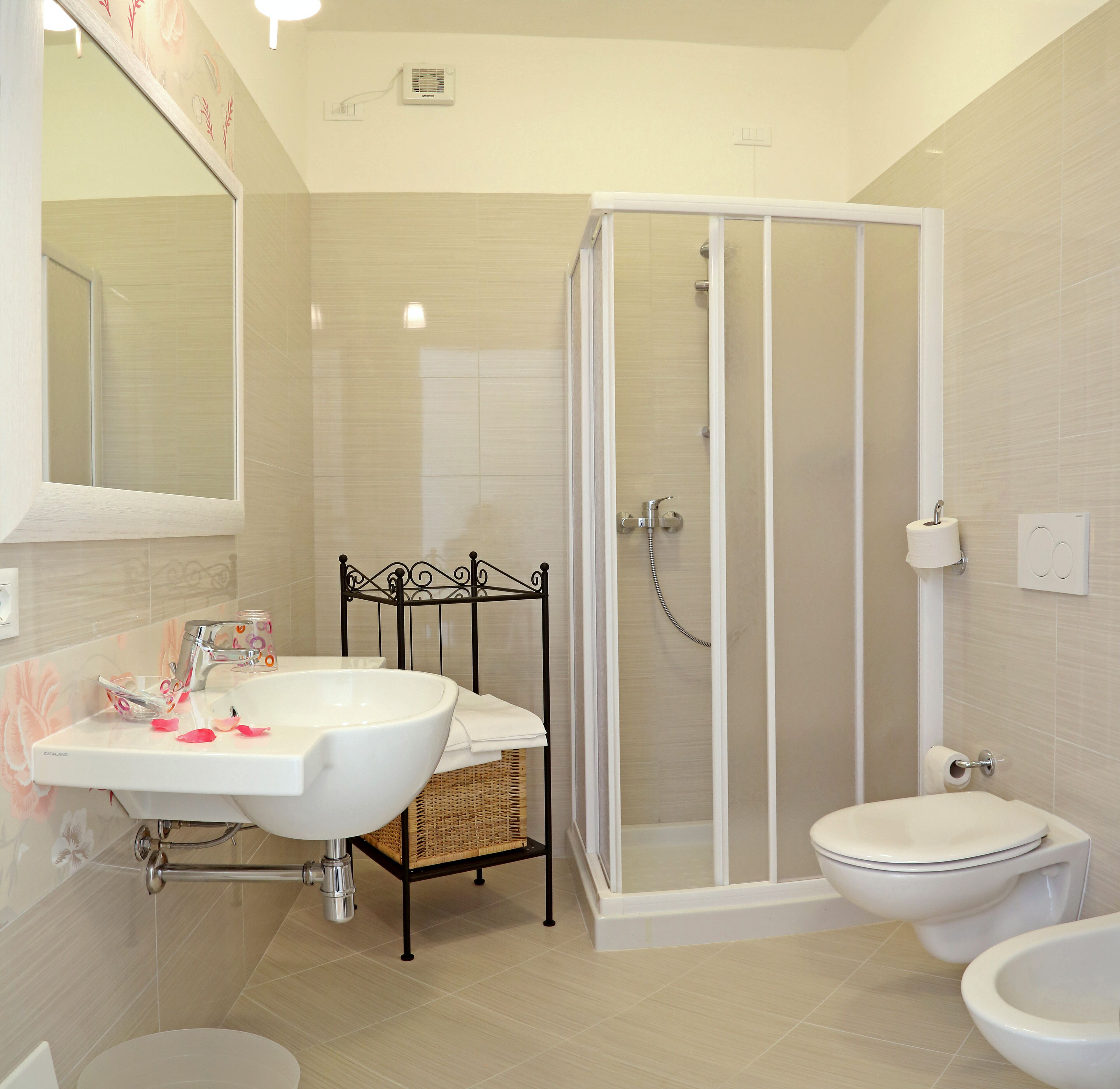 A bathroom with a white sink, a glass shower enclosure, a toilet, and a bidet.