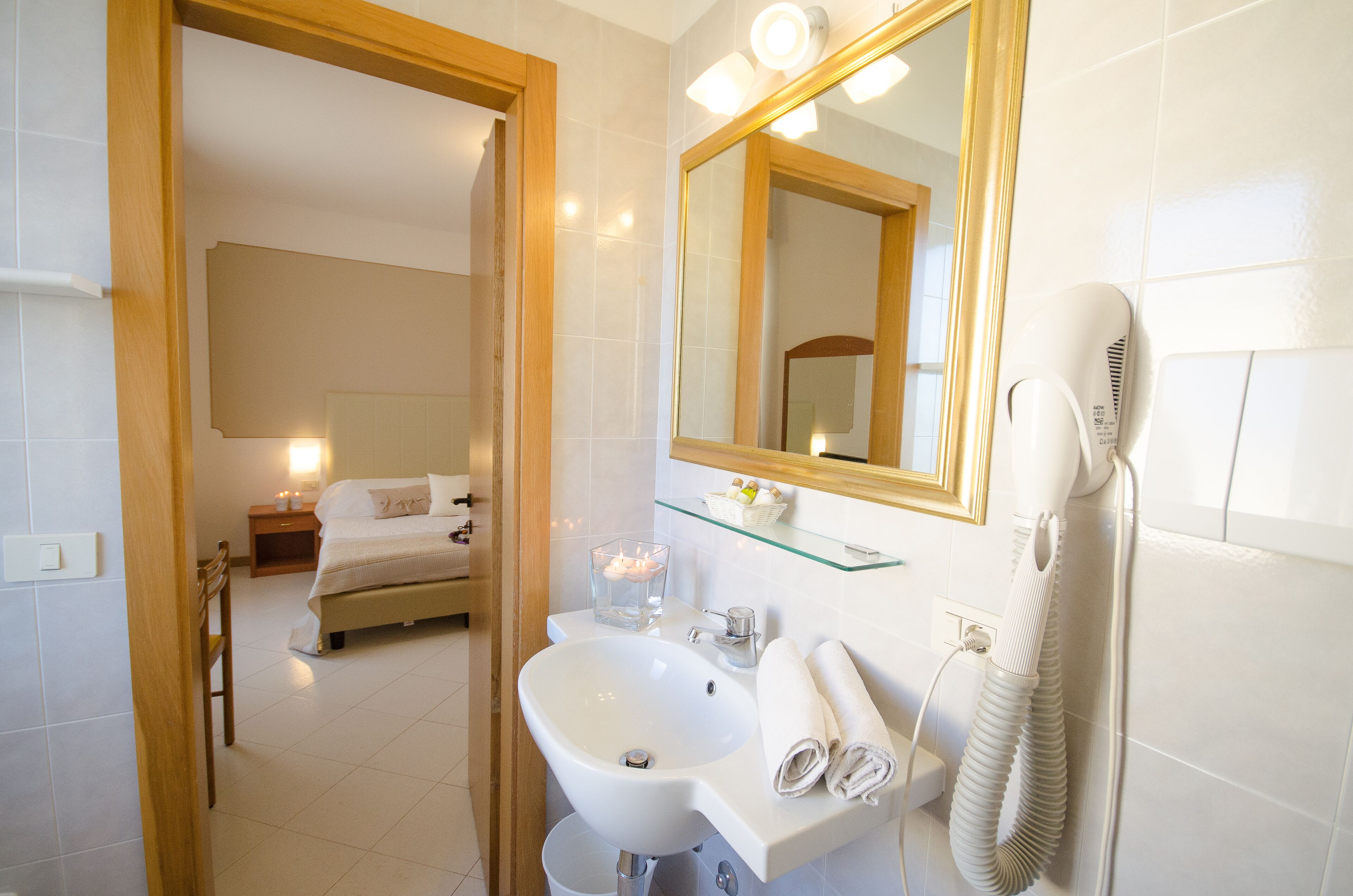 Un baño de hotel con lavamanos, espejo y secador de pelo.