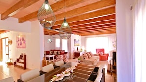Un vaste espace de vie comprenant un ensemble de canapés, une table à manger et des luminaires suspendus.