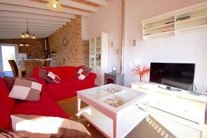 A living room with a red sofa, a glass coffee table, a TV, and a bookshelf.