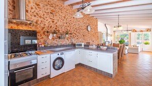 Une cuisine moderne avec un mur en pierre, des appareils électroménagers intégrés et un coin repas offrant une vue agréable.