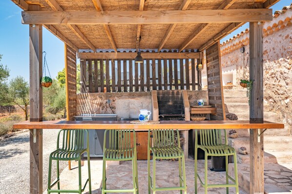 An outdoor wooden pergola with a grill and seating area.