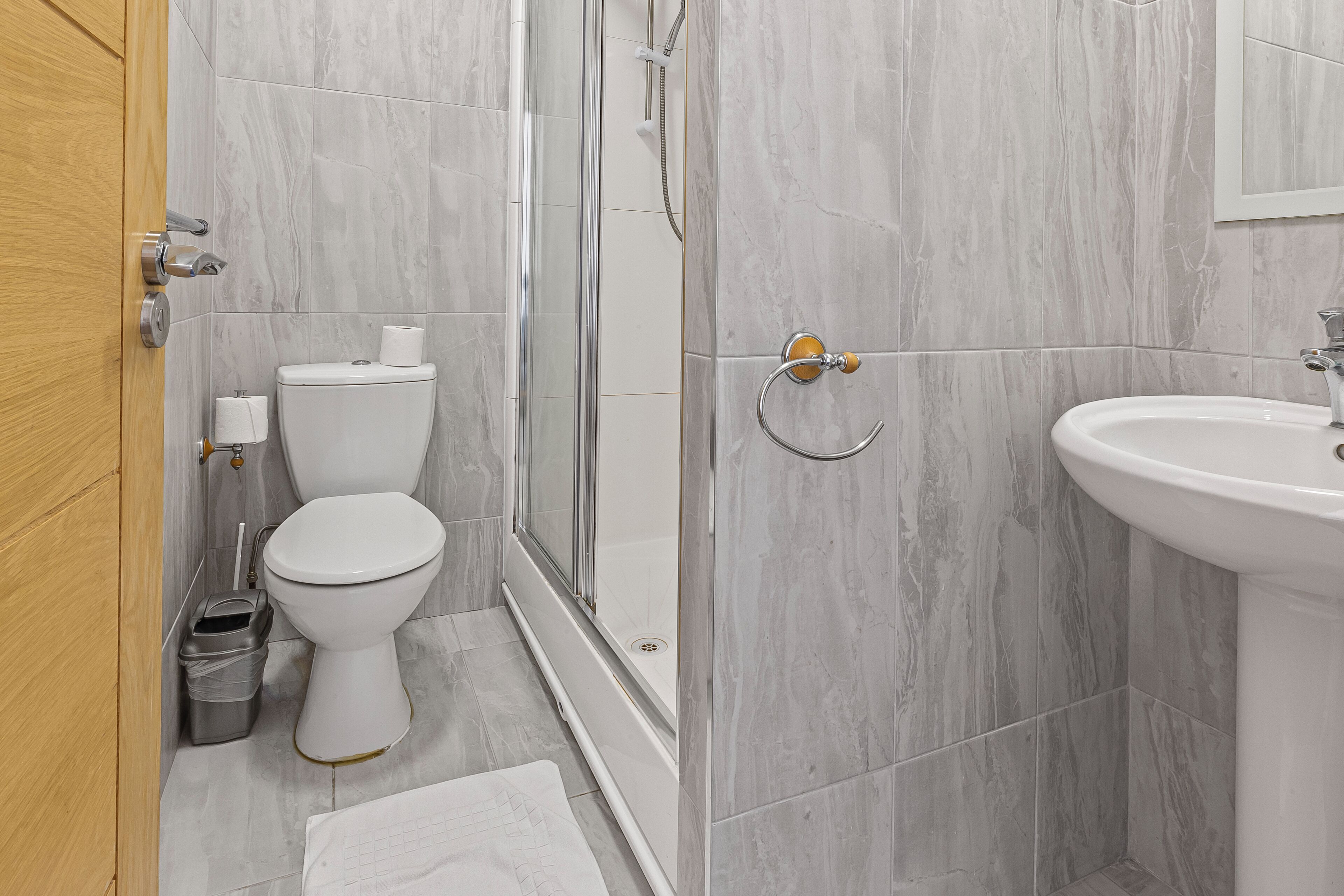 Une salle de bain équipée de toilettes, d’une douche, d’un lavabo et d’une porte en bois.