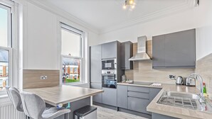 Una cucina moderna con mobili grigi, forno integrato, lavello in acciaio inossidabile e una finestra con vista sulla città.