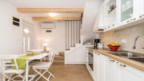 Una cocina moderna con armarios blancos, encimera de madera y un tazón rojo con fruta.
