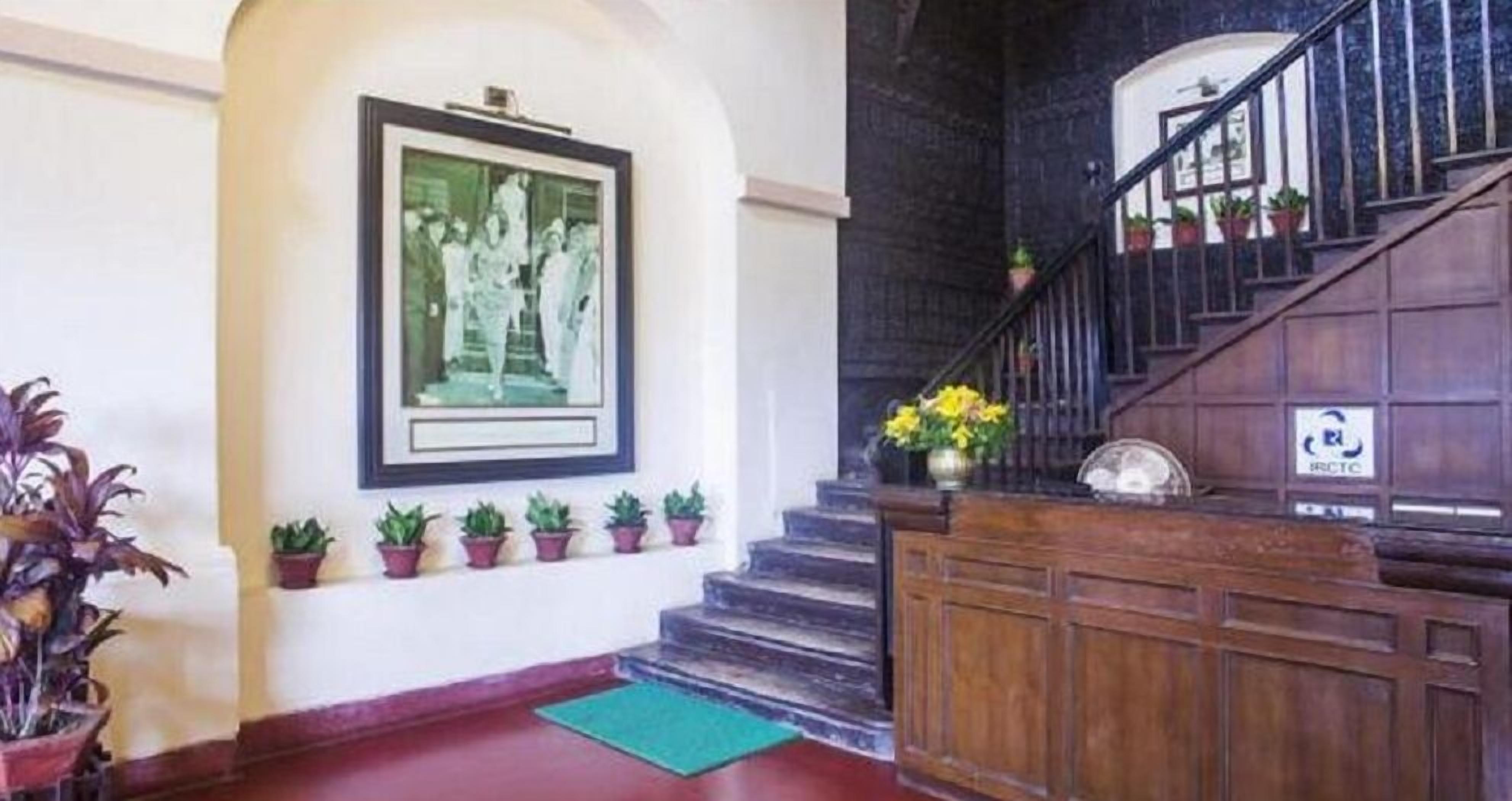 Una zona de recepción con una escalera, una fotografía en un marco en la pared y plantas en macetas.