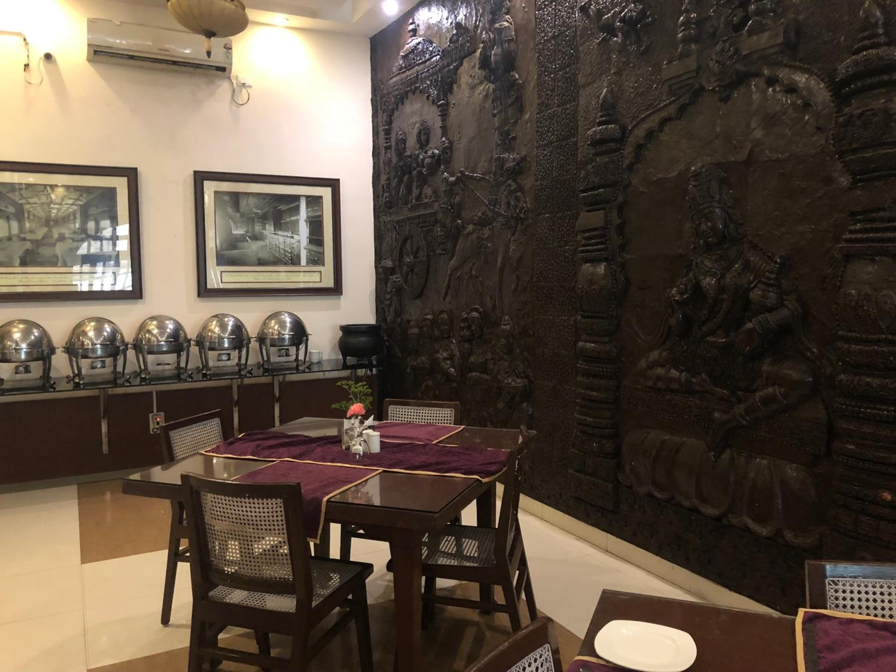 Un comedor con una mesa dispuesta para cuatro personas, rodeada de sillas. En la pared sobre la mesa hay cuadros enmarcados.