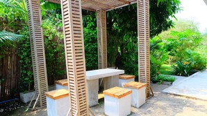 A wooden pergola structure with a white table and benches. - Villa Franjipani Maerim (Mae Rim)