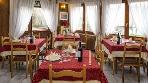 Zona de menjador amb diverses taules preparades per a una estada, amb caires de fusta i tovallons vermells.