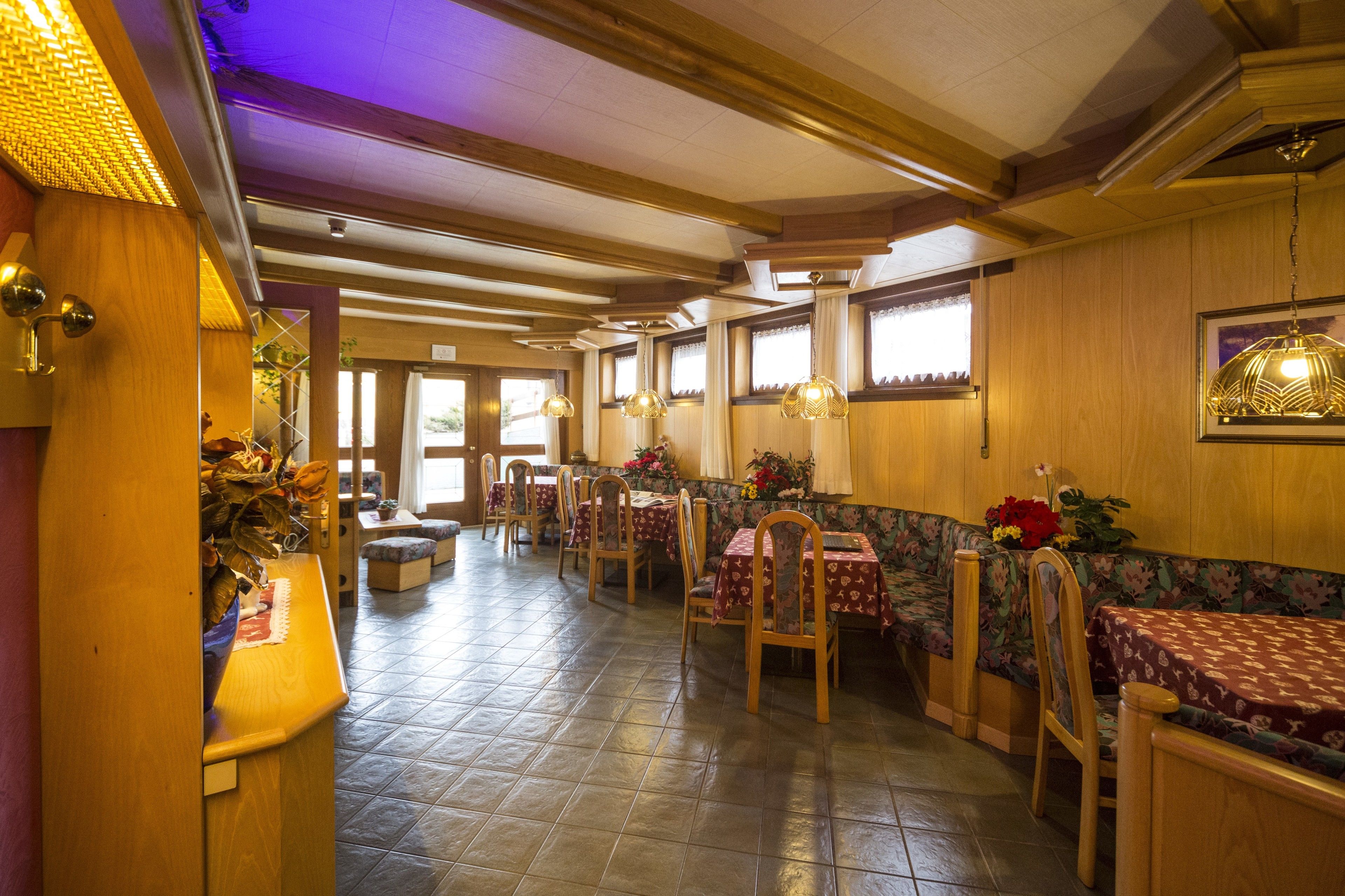 A restaurant with wooden beams, tiled floors, and tables with floral tablecloths.