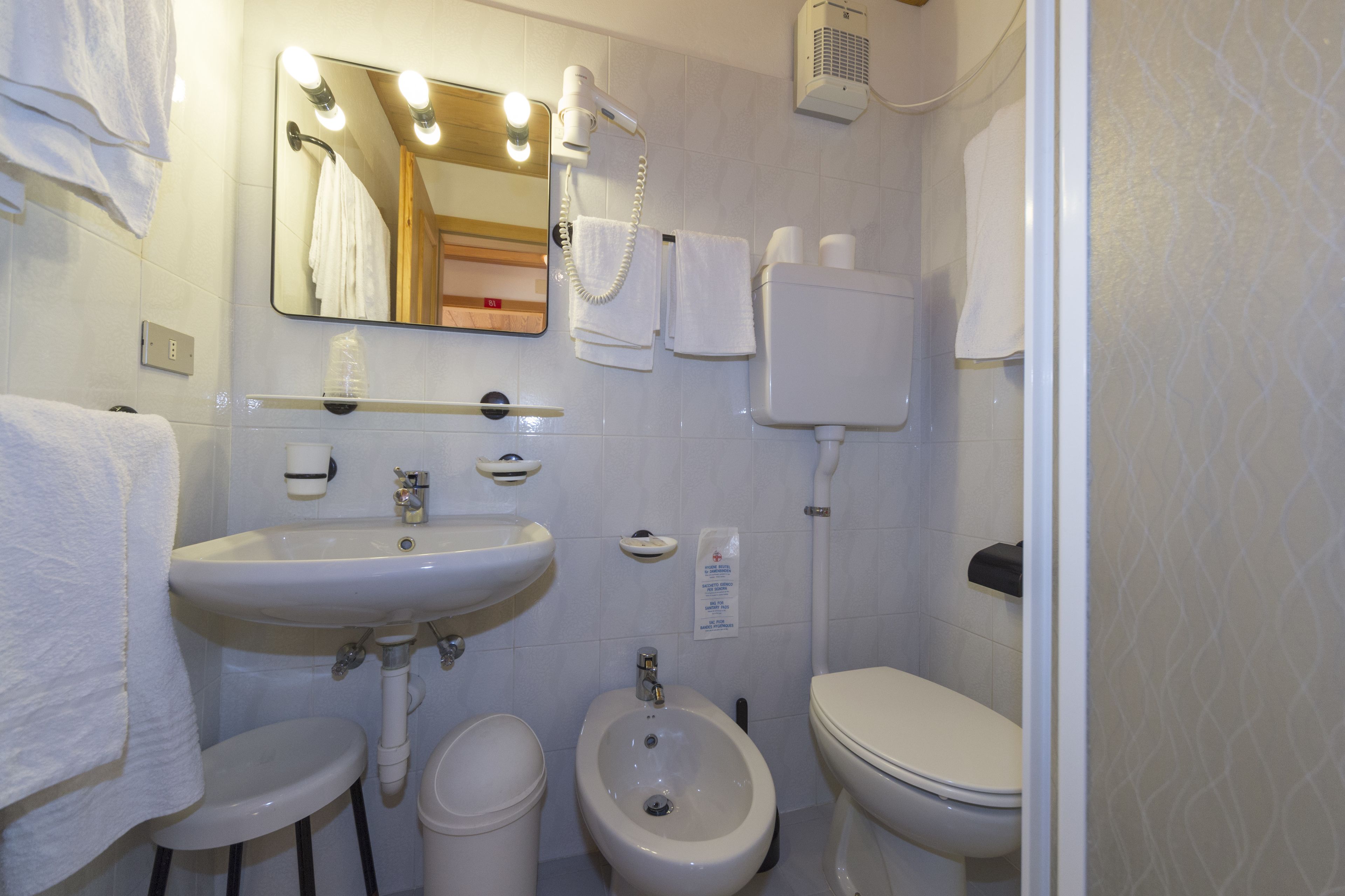 Un baño con lavamanos, bidé, inodoro y espejo con iluminación.