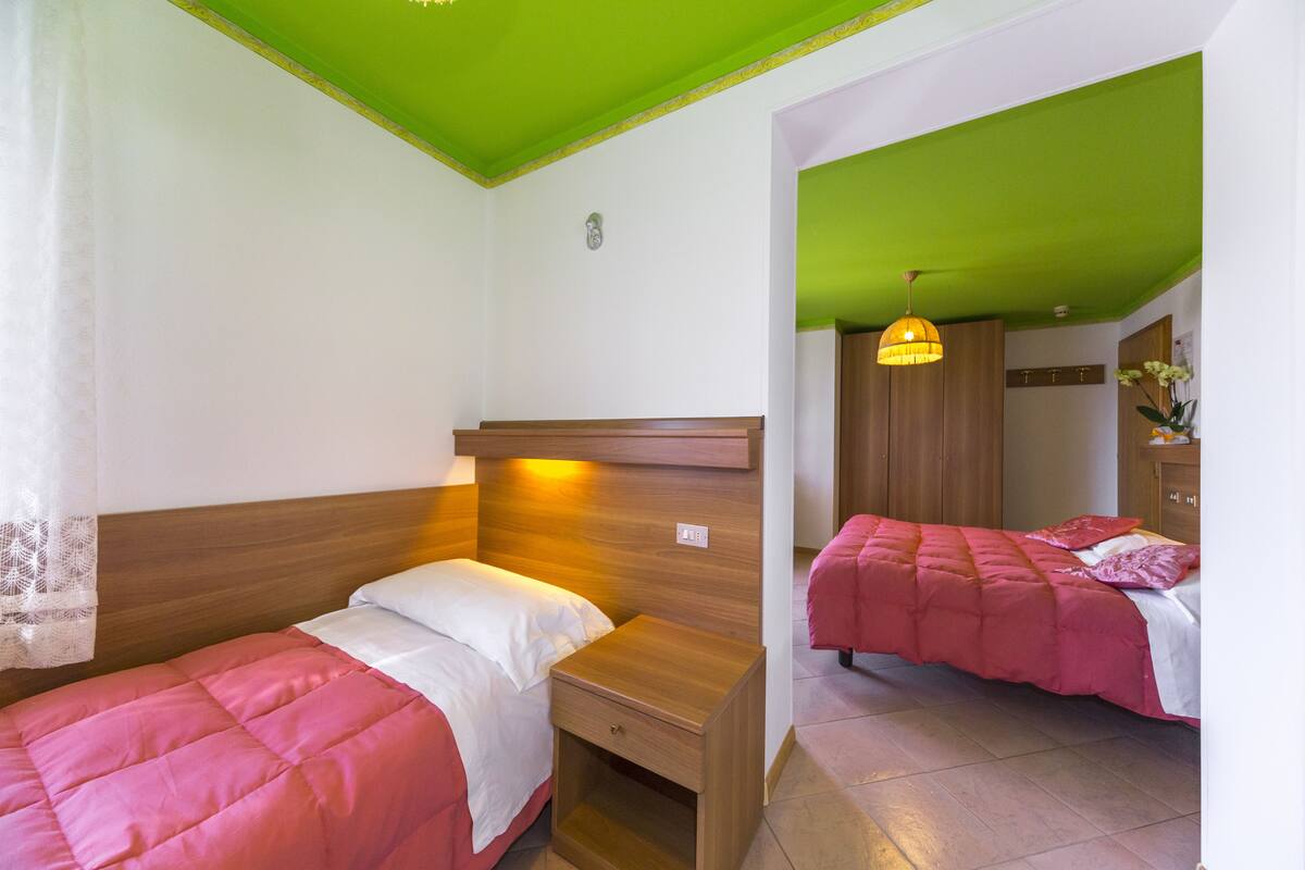 A room with two beds, each with a wooden headboard and a bedside table.