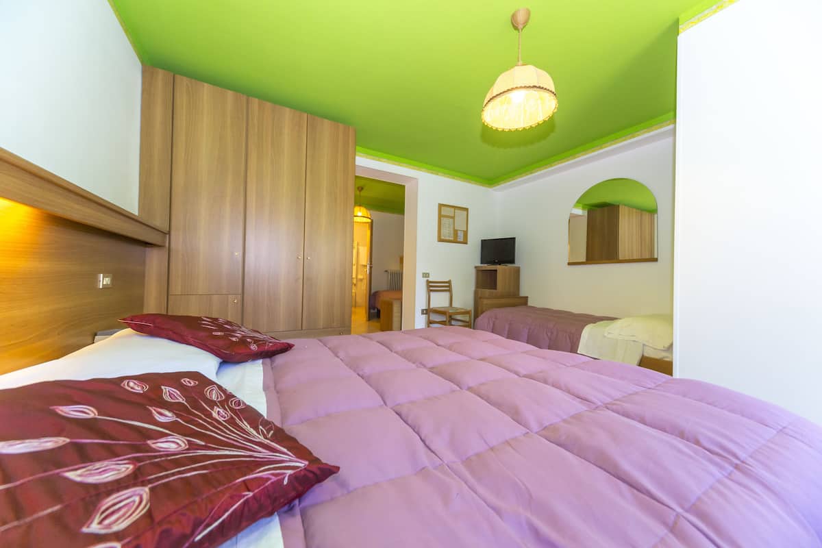 A bedroom with a large bed, wooden wardrobe, and a green ceiling.