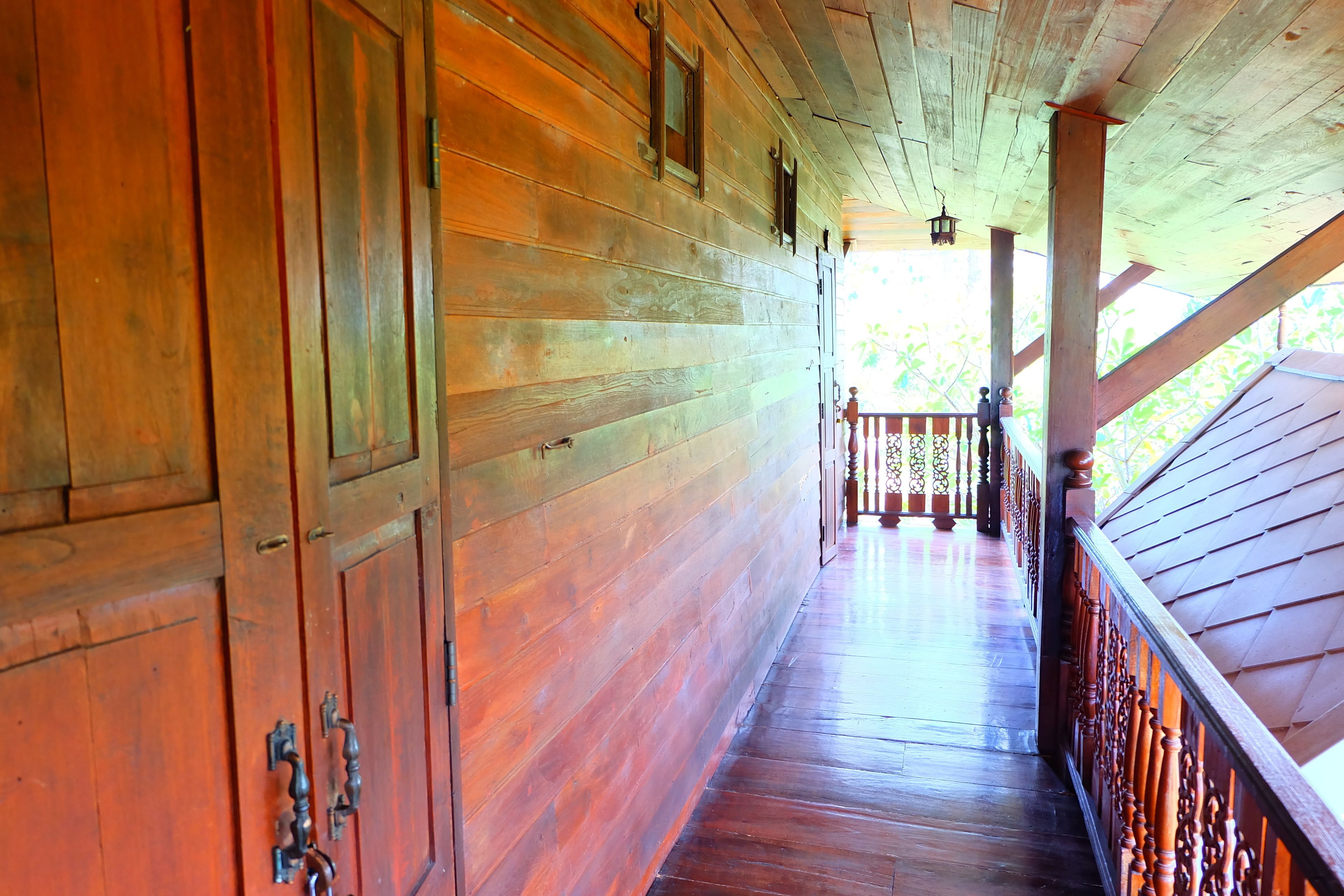 A wooden corridor with a wooden railing and a view of the outdoors.