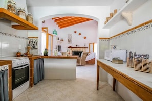 A kitchen with a central island, wooden beams, and a white tiled backsplash. - 44246 Finca Sa Cova, Spain (Petra)