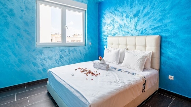 A bedroom with a large bed, a window, and blue walls.