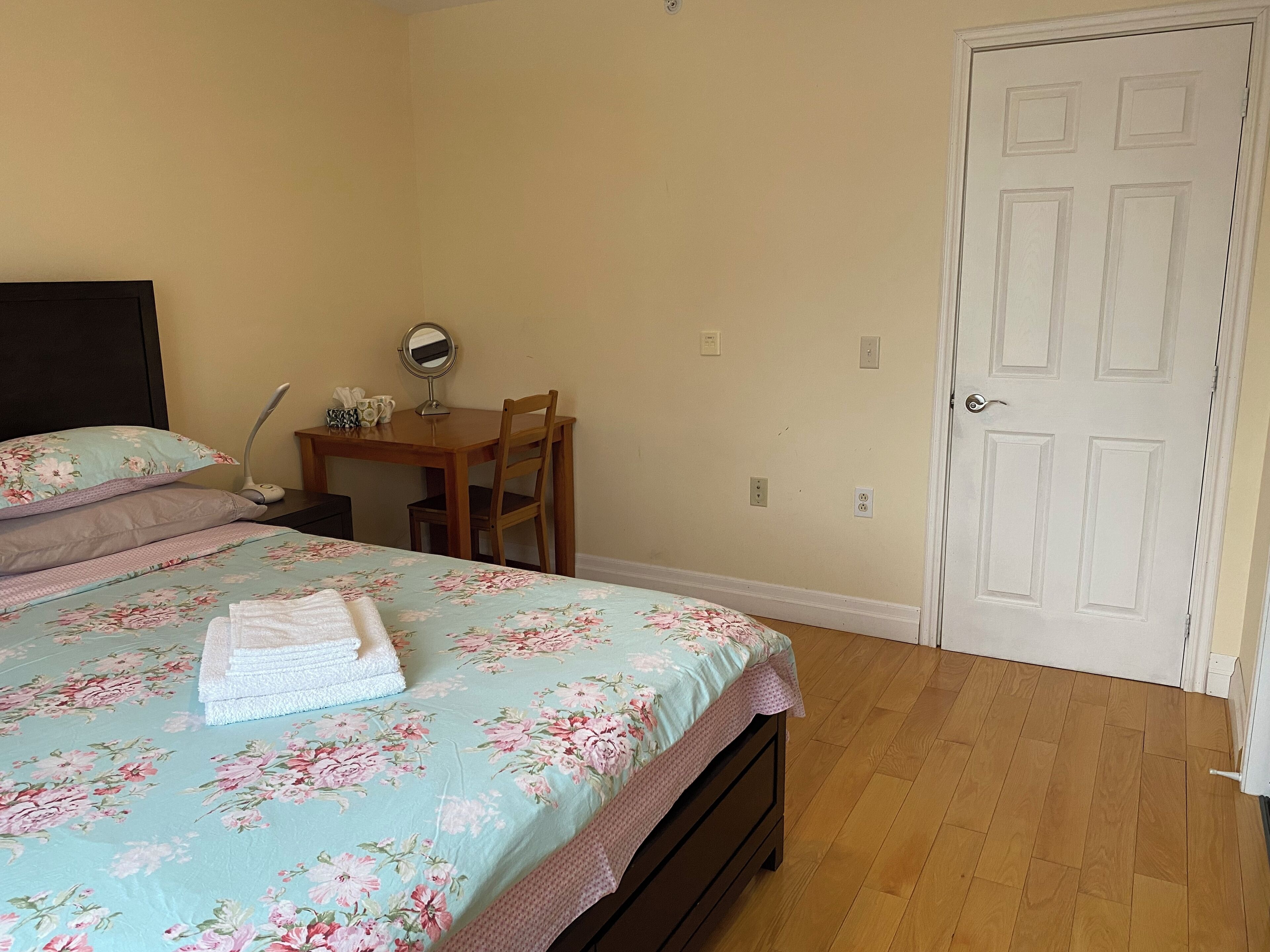 Un dormitorio con una cama, un escritorio, una silla y una puerta.