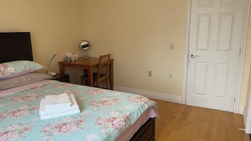 Un dormitorio con una cama, un escritorio, una silla y una puerta.