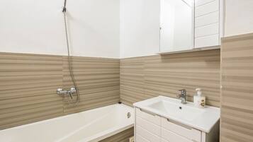 Een aparte badkuip en douche, een diep bad, badjassen, handdoeken