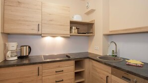 A modern kitchen with wooden cabinets, a built-in oven, a coffee maker, and a sink. - Dachappartement (Berchtesgaden)