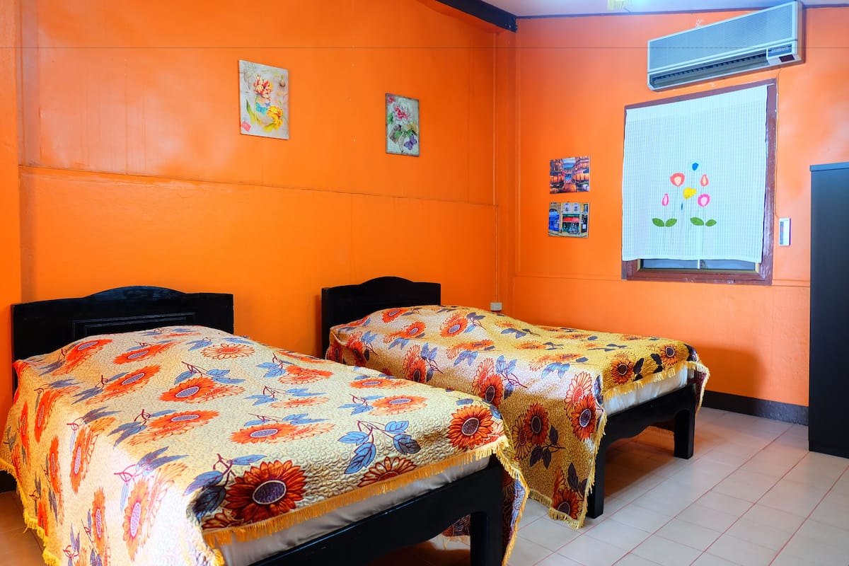 Una habitación con dos camas, paredes anaranjadas y colchas con estampado floral.