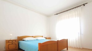 Een slaapkamer met een houten bed, een nachtkastje en een bedtafel met een lamp.