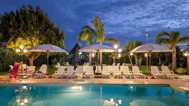 A poolside area with lounge chairs, umbrellas, and a slide. - Beautiful apartment in Marsala -TP- with outdoor swimming pool (Marsala -TP-)