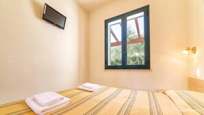 A hotel room with a bed, a window with a view of trees, a flat-screen TV, and a bedside lamp. - Beautiful apartment in Marsala -TP- with outdoor swimming pool (Marsala -TP-)