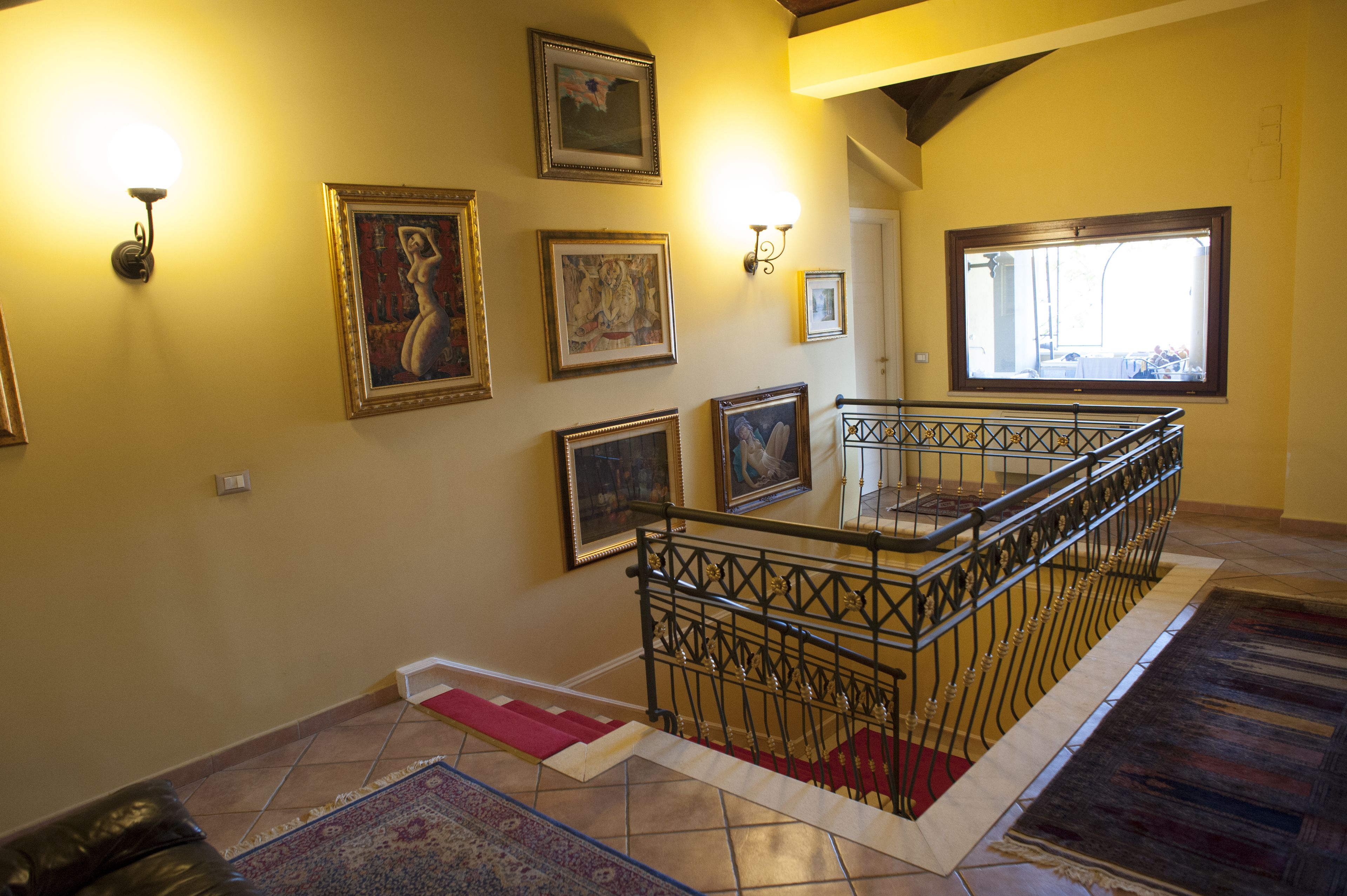A staircase with a metal railing, a red carpet, and a patterned rug.
