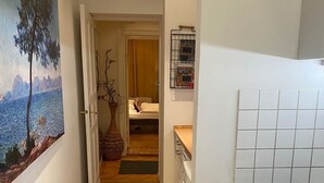 A narrow hallway leading to a bedroom with a bed, a washing machine, and a kitchen area with a stove and sink. - Super * * * apartment at the main station with internet, washing machine (Berlin)