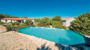 Ein Pool mit Steinstufen, umgeben von Grünpflanzen und Steingebäuden.