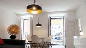 A modern living room with a sofa, dining table, chairs, and a hanging light fixture. - SantoSweethome 2 (Lisbon)