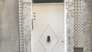 A white door with a diamond-shaped handle, marked with the number 40, set in a textured wall with blue and white patterned tiles. - SantoSweethome 2 (Lisbon)