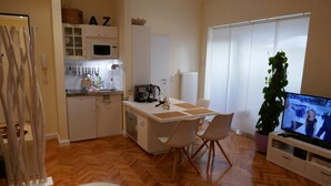A modern kitchen with white cabinets, a dining area with a white table and chairs, a television, and a potted plant. - Super * * * * * * Apartment at the main station with terrace, WiFi, washing machine.  (Berlin)