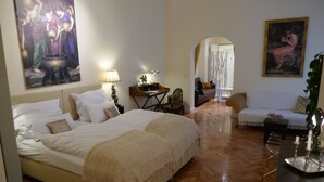 A hotel room with a large bed, a desk with a lamp, a chair, and a sofa. There are paintings on the walls and a wooden floor. - Super * * * * * * Apartment at the main station with terrace, WiFi, washing machine.  (Berlin)