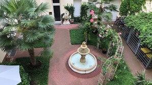 A courtyard with a central fountain, surrounded by lush greenery and a brick pathway. - Super * * * * * * Apartment at the main station with terrace, WiFi, washing machine.  (Berlin)