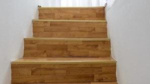 Un escalier en bois, avec des murs blancs et un rideau blanc.