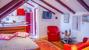 Une chambre à coucher avec un lit, un fauteuil rouge, une petite table avec une plante et un canapé rouge.