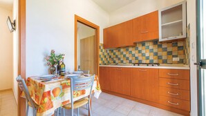 Uma cozinha compacta com armários de madeira, painel de azulejos e uma área de refeições com mesa posta para dois.