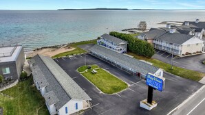 A motel with a parking lot, a grassy area, and a view of the sea. - Bayview Lakefront Motel (St Ignace)