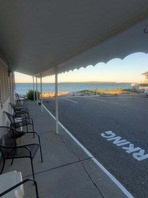 A covered outdoor seating area with a view of the sea. - Bayview Lakefront Motel (St Ignace)
