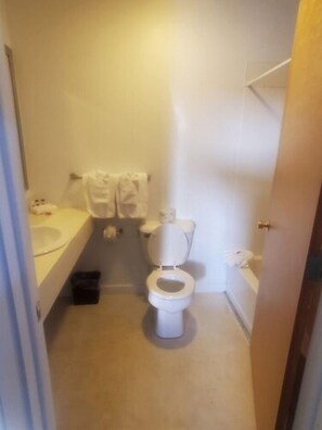 A small, clean bathroom with a toilet, sink, and towel rack. - Bayview Lakefront Motel (St Ignace)